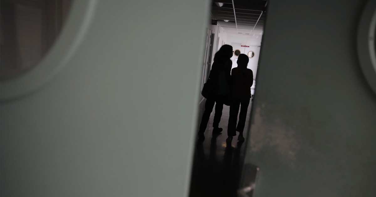 two people standing in dark hallway